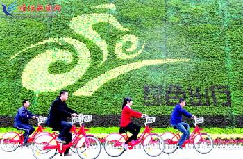 市民騎公共自行車路過市人民廣場一處花壇。記者 張馳